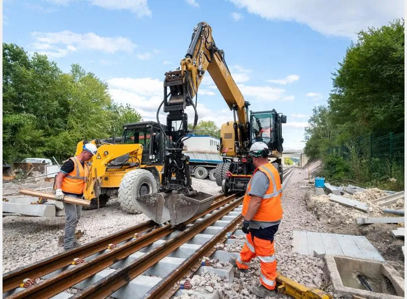 Travaux de terrassement en emprise ferroviaire : pelle rail-route et opérateur sur la voie